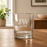 Personalised engraved whiskey glass with JW initials and est 1995 date on wooden table