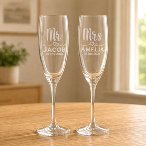 Clear glass Mr and Mrs champagne flutes with engraved Jacob and Amelia names on wooden table