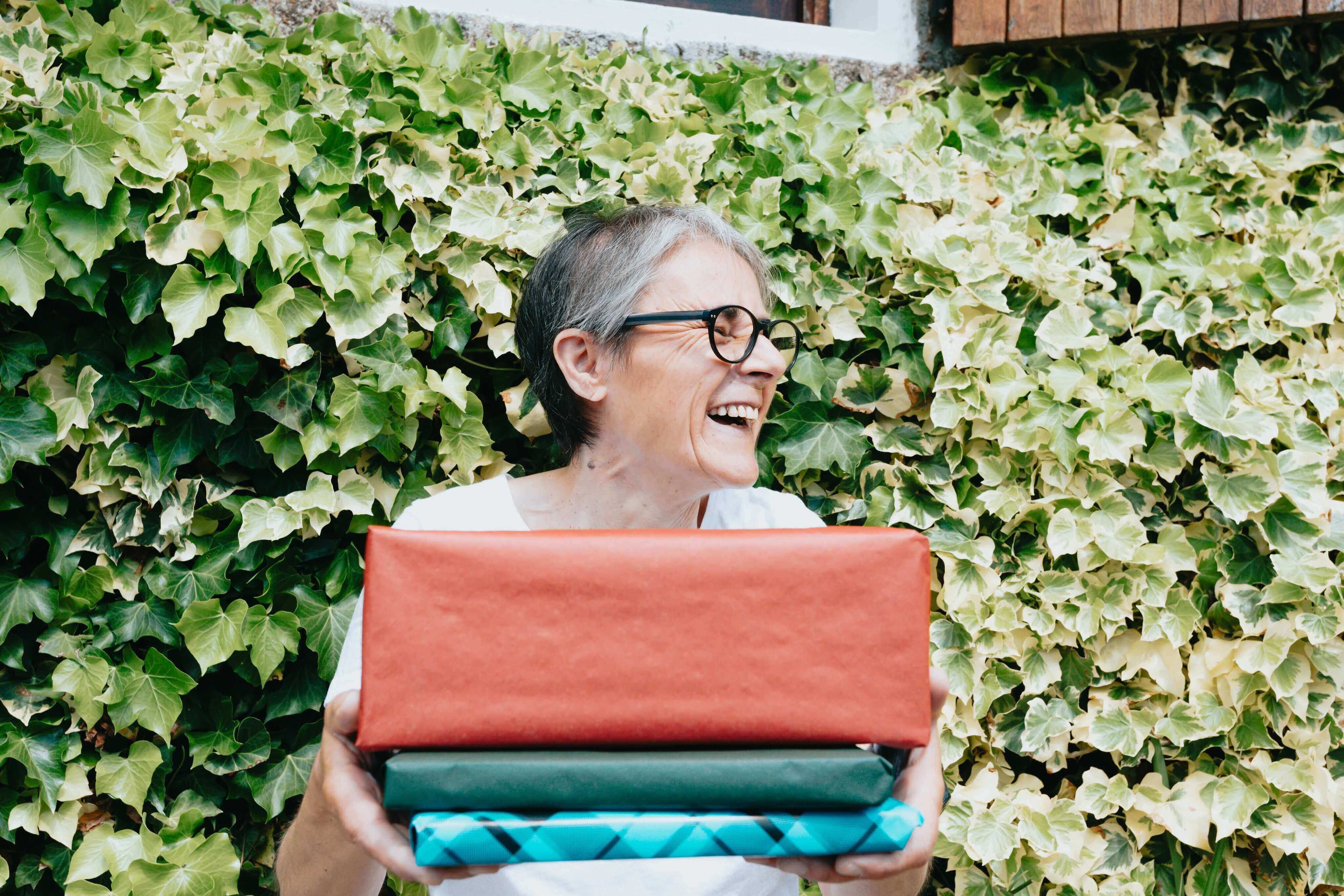 woman-holds-a-stack-of-gifts-and-smiles-wide